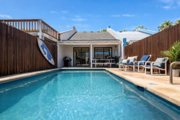 Sunlit retreat with a private pool framed by coastal wood accents and breezy patio charm. Perfect for slow mornings or sunset dips, this space blends warmth and ease—inviting guests to unwind, connect, and savor island living at its best.
