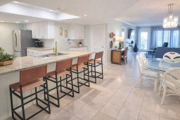 Modern Coastal Retreat: Open-Concept Kitchen, Glass Dining, Blue Accents, Steps to Beach & Balcony Views