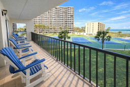 Oceanview Balcony with Tennis Courts & Resort Amenities – Relax in Blue Adirondack Chairs Overlooking Palm Trees, Coastal Breeze, and Sunny Skies. Perfect for Beach Getaways, Family Fun, and Active Retreats.