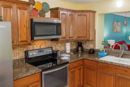 Cook with ease in this fully equipped kitchen featuring granite countertops, modern stainless steel appliances, rich wood cabinetry and a cozy open layout that flows into the living area perfect for preparing meals and entertaining with family.