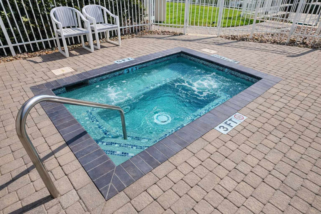 Relax and recharge in this sparkling outdoor tub with bubbling jets, surrounded by a clean paver deck and sunny fenced patio—perfect for unwinding after a beach day or enjoying a peaceful evening soak.