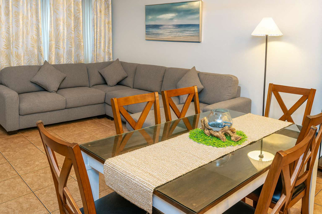 Cozy Living & Dining Retreat
Plush gray L-shaped sectional anchors airy living space with sea art, lamp glow, sheer drapes. Rustic wood table seats 6, adorned with coral accents & runner. Inviting coastal haven for family gatherings.