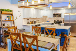 Modern Coastal Kitchen at Saida #3305
Sunlit open kitchen features crisp white cabinets, gleaming stainless steel appliances, striking navy quartz island seating 4-6. Rustic wood table, coastal shelves with greenery—ideal for beachy breakfasts.
