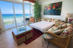 Beachfront Bliss: Tropical Living Room with Ocean Views, Pull-Out Bed, Balcony Seating, Parrot Art, and Coastal Decor — Steps from the Sand
