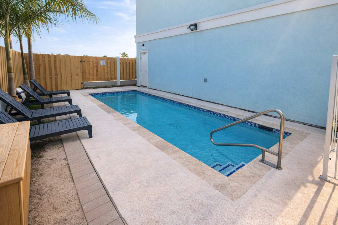 Private Pool Retreat • Walk to Beach • Palm-Lined Deck • Light Blue Coastal Vibe • Lounge Chairs + Bench • Clean, Bright, Relaxing Escape • Perfect for Couples or Small Families