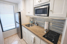 Modern Compact Kitchen with Stainless Steel Appliances, Two-Burner Cooktop, Microwave, and Natural Light—Perfect for Extended Stays or Weekend Getaways.