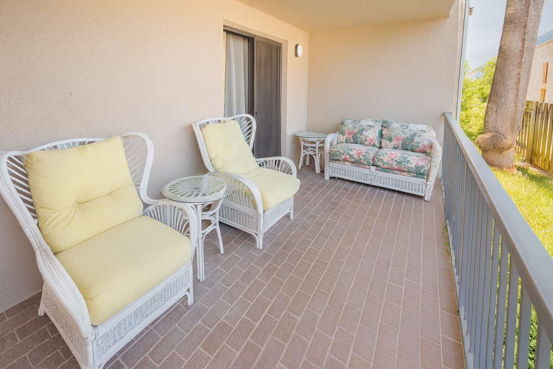 Sunny Wicker Balcony Retreat
White wicker chairs and loveseat with yellow cushions invite lounging on this breezy balcony. Glass-top tables, sliding doors to interior & railing views of palms & greenery—ideal for morning coffee or evening relaxation.