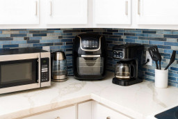 Cook with ease in this fully equipped kitchen—microwave, air fryer, coffee maker, kettle, and utensils await against stylish blue tile. Enjoy all the comforts for homemade meals or quick snacks before hitting the beach!