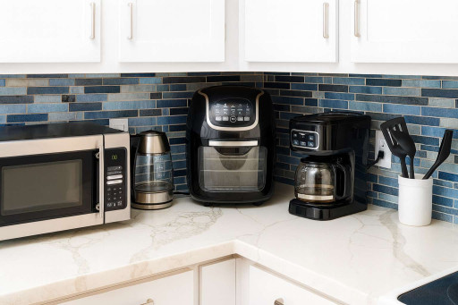 Cook with ease in this fully equipped kitchen—microwave, air fryer, coffee maker, kettle, and utensils await against stylish blue tile. Enjoy all the comforts for homemade meals or quick snacks before hitting the beach!