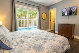 Serene Poolside Master Bedroom
Elegant bed w/ floral bedding, wall TV & French doors to sparkling pool! Cozy dresser, lamp lighting, serene gray tones. Wake to tropical views—pure beach luxury!