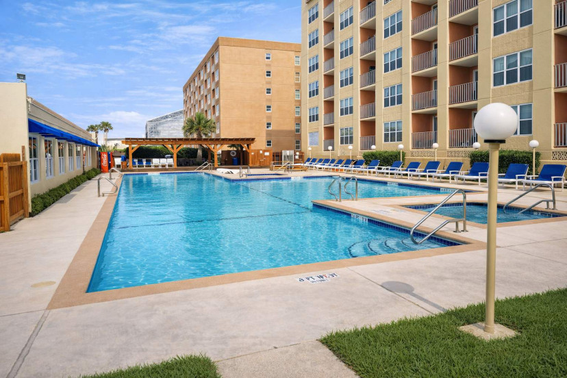 Resort-style pool retreat with shaded pergola, lounge chairs, and Gulfview II balconies—perfect for relaxing under the sun.