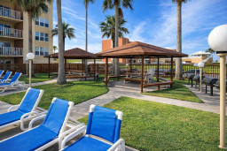 Palm-shaded picnic area with BBQ grills, lounge seating, and tropical vibes—perfect for outdoor dining, relaxing, and social gatherings just steps from your stay.