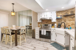 Enjoy cooking and dining in style with a modern kitchen featuring stainless appliances, farmhouse sink, and a chic stone backsplash. Gather at the spacious dining table for memorable meals in a bright, open layout with coastal touches throughout.