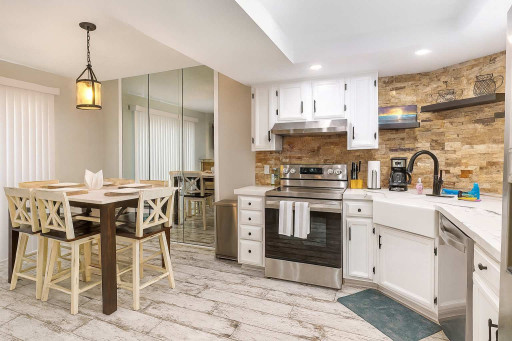 Enjoy cooking and dining in style with a modern kitchen featuring stainless appliances, farmhouse sink, and a chic stone backsplash. Gather at the spacious dining table for memorable meals in a bright, open layout with coastal touches throughout.