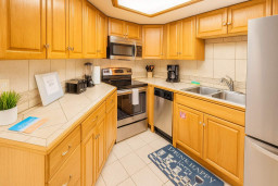 Modern kitchen with stainless steel appliances, oak cabinetry, tiled counters, and double sink. Includes coffee maker, toaster, blender, and welcome binder. Bright, clean, and fully equipped—perfect for extended stays or weekend getaways.