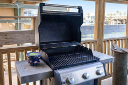 Covered patio with clean gas grill, perfect for outdoor cooking and entertaining. Ideal for beachside BBQs, family meals, or sunset grilling with a view.