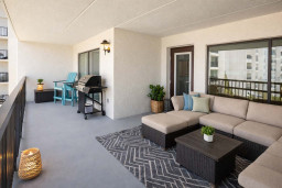 Serene coastal retreat featuring a spacious balcony with plush sectional seating, chic rugs, and a modern grill setup. Perfect for morning coffee or sunset gatherings, this airy outdoor lounge blends comfort and style for an unforgettable stay.