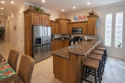 Modern kitchen with granite counters, stainless steel appliances, woven barstools, and vibrant decor. Bright, spacious layout ideal for cooking, entertaining, and relaxing. Natural light and stylish touches throughout.