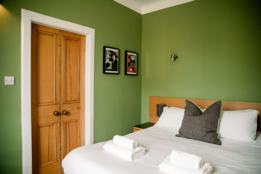Restful bedroom w/ soft bedding, accent wall & calming green tones throughout