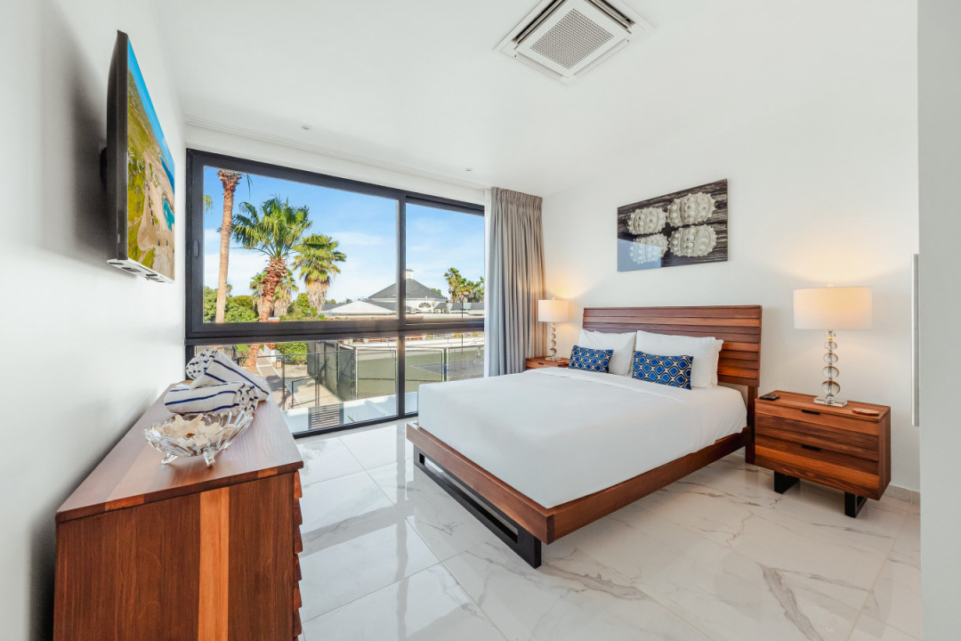 Wake up to palm tree views and plenty of natural light in this bright, comfortable bedroom — a peaceful spot to recharge after a day by the beach.