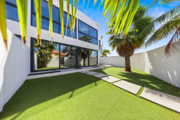 Private garden with palm trees and a sunny lawn—perfect for relaxing or enjoying a bit of outdoor time.