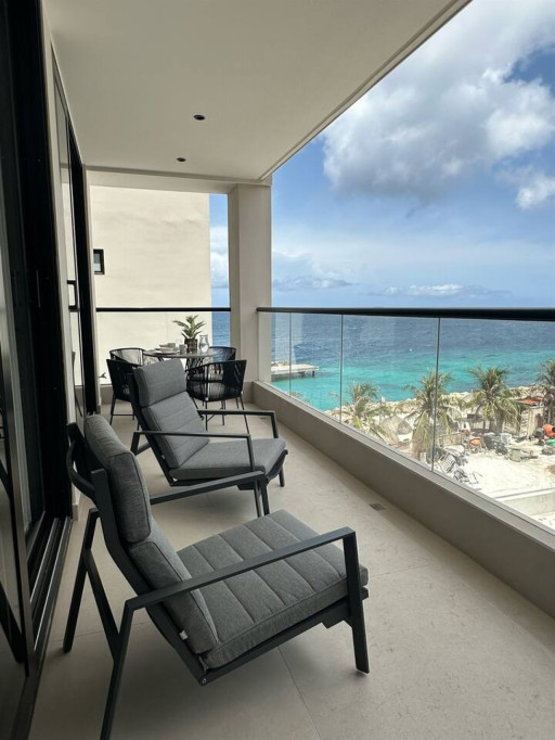 Enjoy the fresh ocean breeze and beautiful sea views from the spacious private balcony, complete with comfortable lounge seating and an outdoor dining area.
