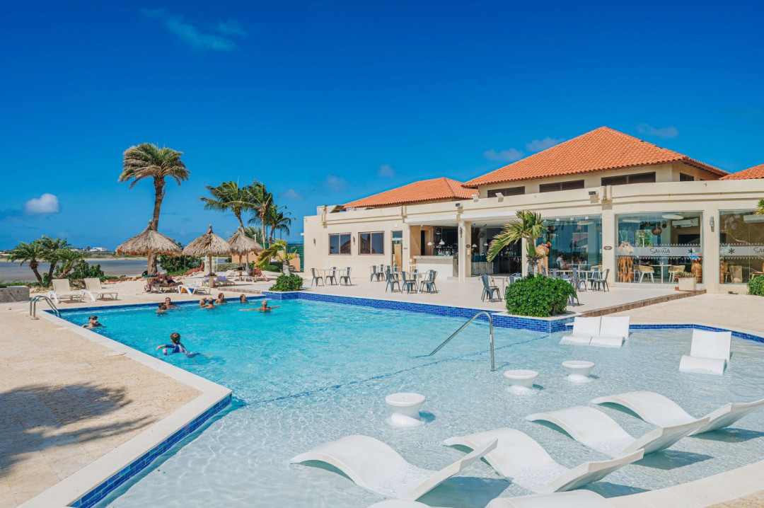 The Gold Coast resort swimming pool, one of three pools. Take a refreshing swim complete with shallow lounging areas, comfortable sun chairs, and plenty of space to relax under the Aruba sun.