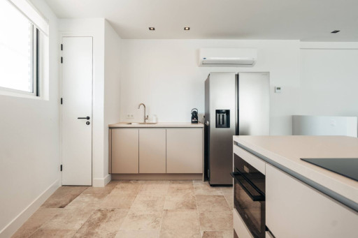 A modern kitchen with sleek beige cabinetry, a stainless steel fridge, and an open layout with clean lines and neutral tones.