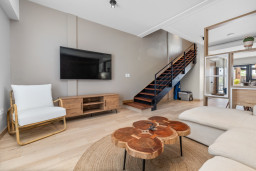 Relax in style! This cozy nook features a comfy chair and a stunning wood coffee table, with a sleek TV for your entertainment. Perfect for winding down!